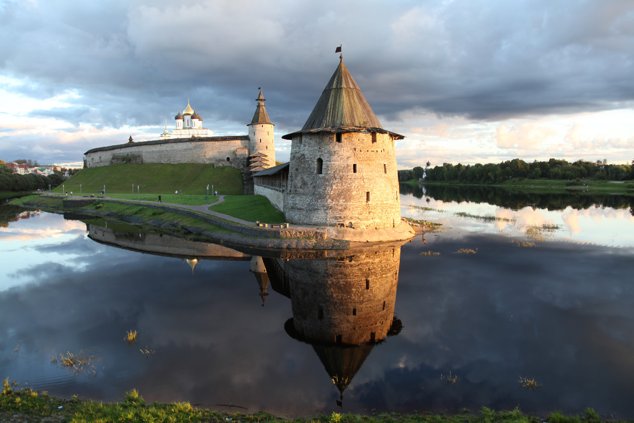 Looking toward the Pskov Kremlin and at the point where the Pskov River flows into the Great River, the Flat Tower stands nearest and is reflected in the Pskov